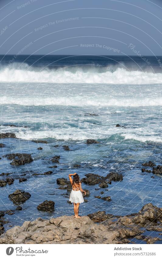 Woman enjoying serene ocean view on weekend getaway woman female looking away waves rocky shore peaceful back view unrecognisable anonymous faceless tranquility