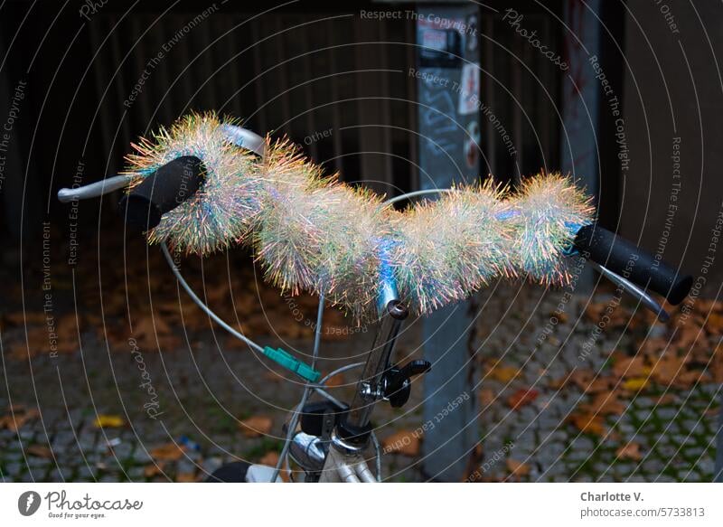 Live unusually | Iridescent garland embellishes a bicycle handlebar Bicycle handlebars Handlebars Means of transport Paper chain Wheel Exterior shot Dazzling