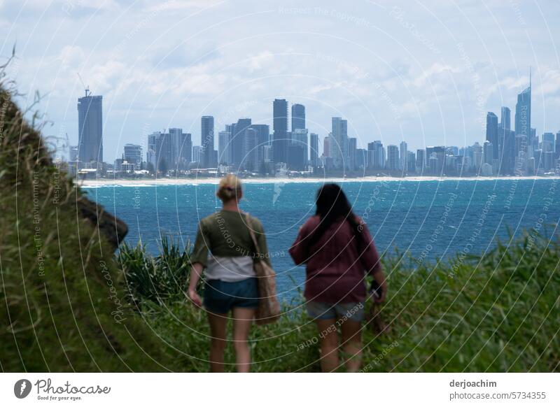 Two on their way towards Surfers Paradise, which takes up the whole picture in the background. In front of them the blue Pacific. hiking in nature Green