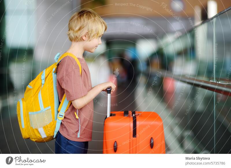 Cute preteen boy is in international airport or on railway station platform. Check-in. Travel, tourism, vacation for family with kids concept departure arrival