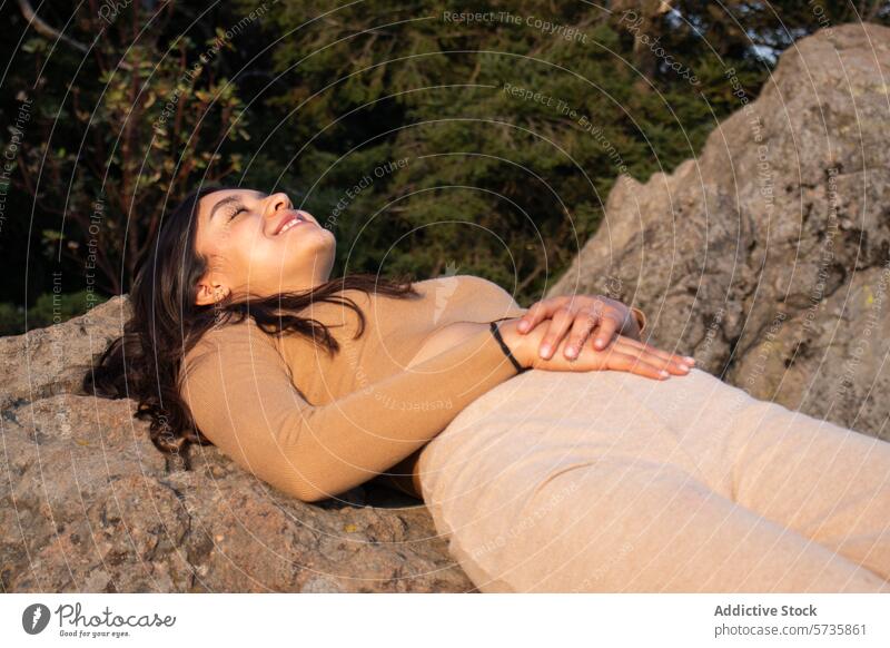 A person exudes happiness while lying back on a rock, surrounded by the tranquil beauty of a natural forest setting relaxed woman joy nature embrace tranquility