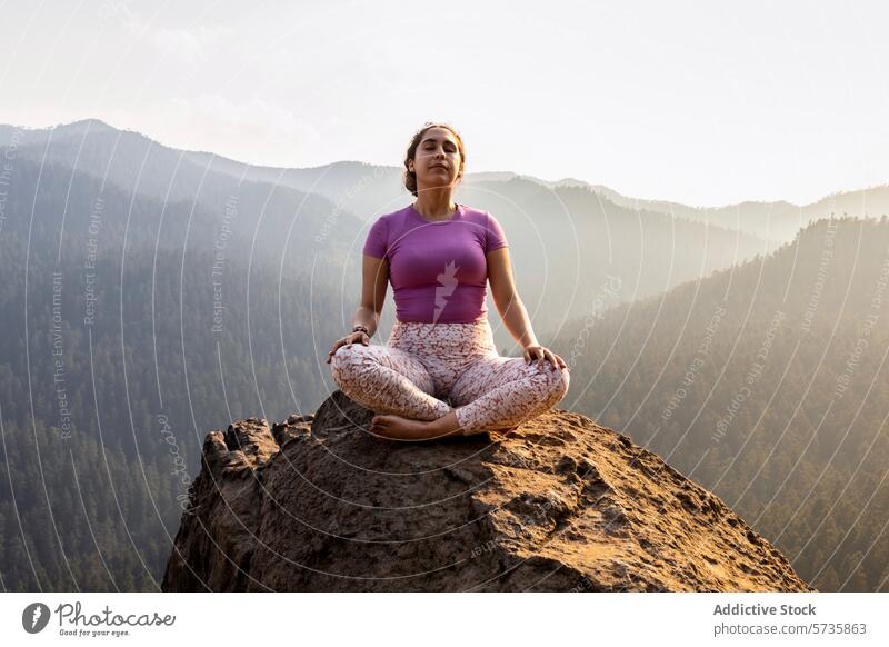 A person finds inner peace while meditating in the lotus position on a mountain summit, with a breathtaking view of the forest below meditation yoga nature