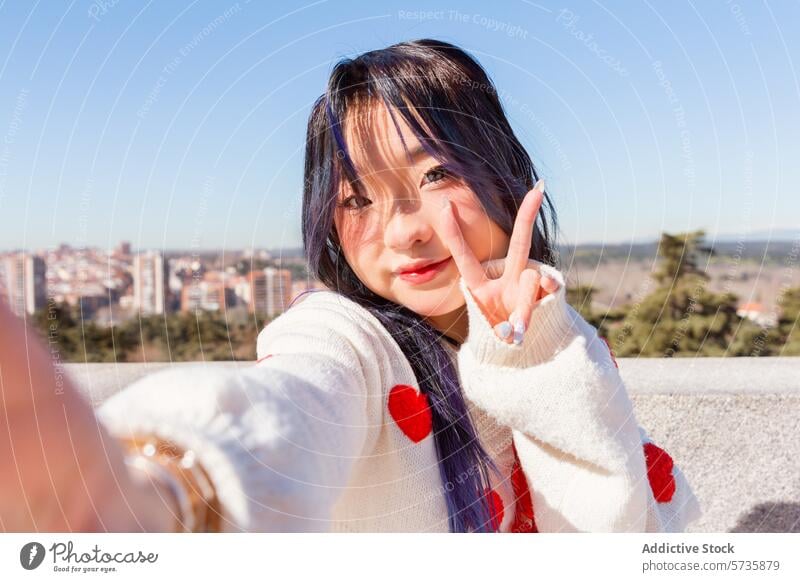 Gen-Z chinese girl posing with peace sign in urban setting gen-z model selfie cityscape young woman dyed hair blue hair white sweater red hearts fashion youth