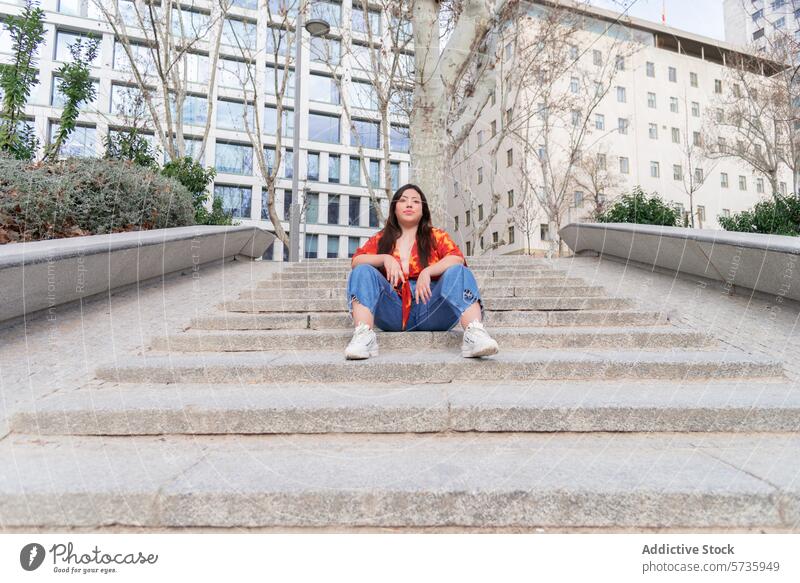 Urban Woman Sitting on Concrete Steps woman city urban sitting concrete stairs looking away thoughtful relaxed casual outdoor street building architecture