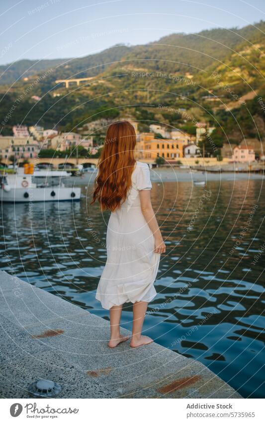 Serene coastal moment captured with red-haired woman red hair white dress barefoot sea town sunset serene scenic overlook waterfront jetty leisure travel
