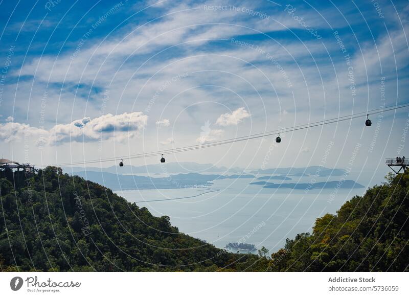Stunning view of Langkawi cable cars gliding above the tropical forest with the archipelago's waters in the distance scenic sky cloud mountain nature Malaysia