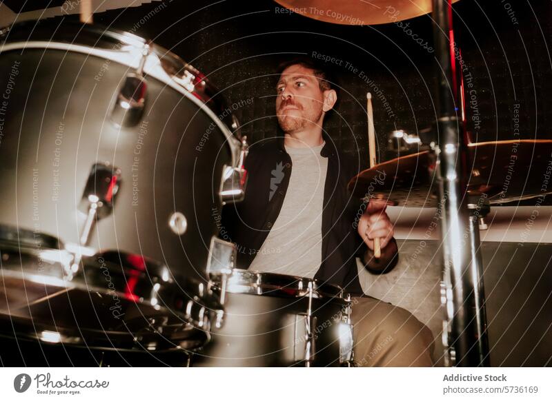 Drummer of a music band playing and concentrating drummer man male stick instrument concentration focus performance musician not looking cymbal snare drum kit