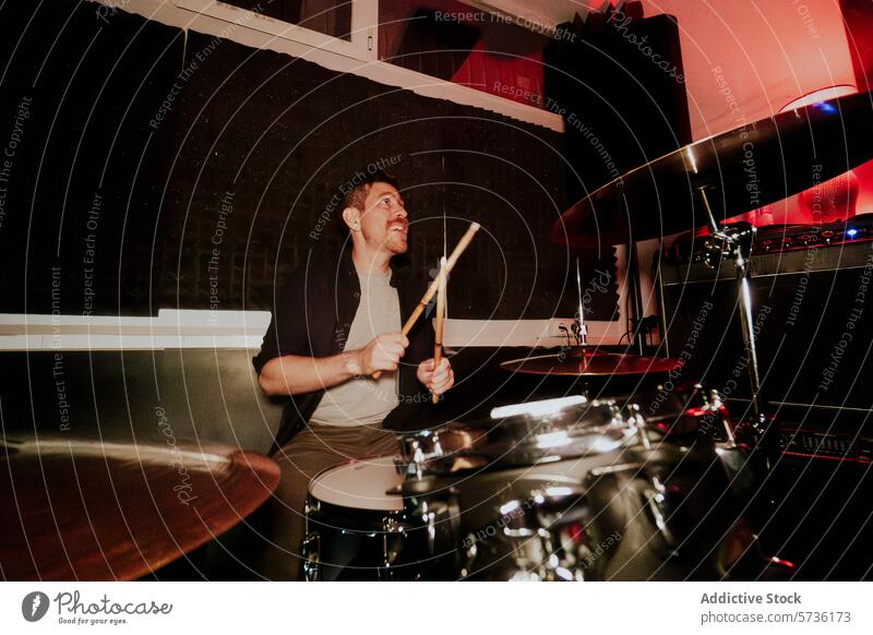 Drummer playing in a band looking away from camera man male drummer drumstick performance cymbal music instrument concentration beat practice rhythm studio