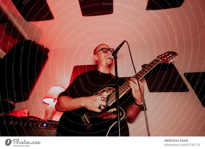 Male musician playing guitar and singing into microphone male man acoustic performance instrument guitar player singer eyes closed vocal strumming chord