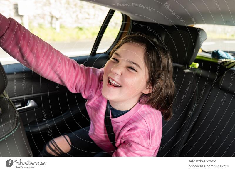 Happy child enjoying a car ride girl happy excitement smiling waving seat vehicle interior journey travel happiness casual clothing transport seat belt