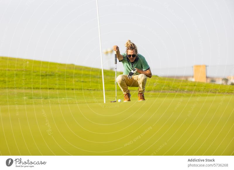 Unique Golfer with Dreadlocks Aiming on the Green golfer course green crouch putt sunlight blonde dreadlocks unconventional sport contemporary aiming athlete