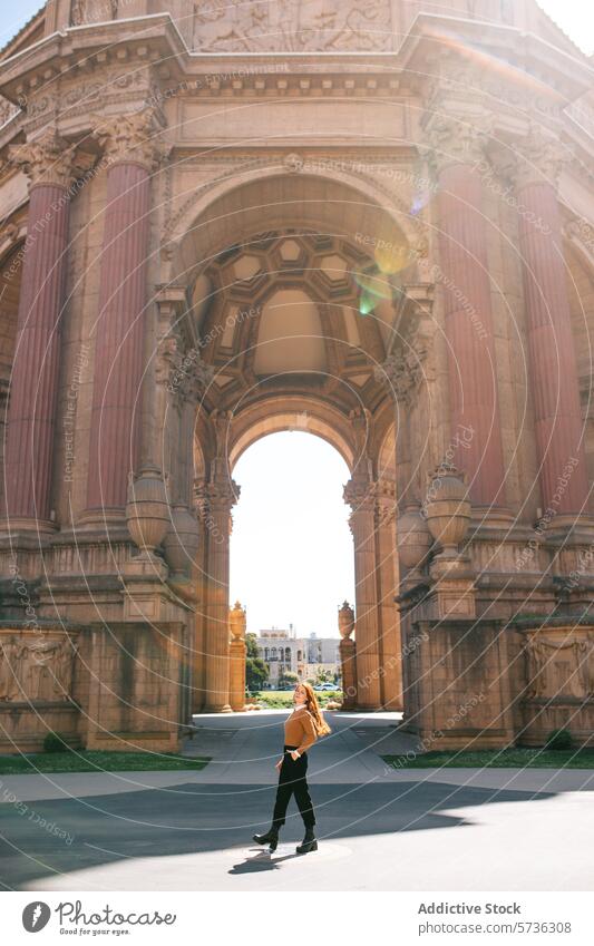 A woman in casual attire walks confidently across the grounds of the Palace of Fine Arts, basking in the San Francisco spring sunshine stroll confidence