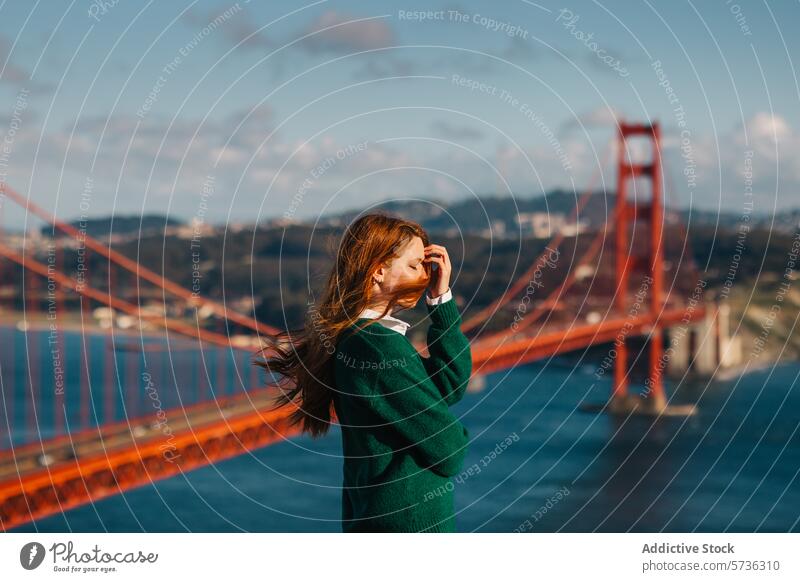 A reflective moment as a woman with wind-tossed hair looks out over the Golden Gate Bridge, embodying the spirit of San Francisco in spring contemplative