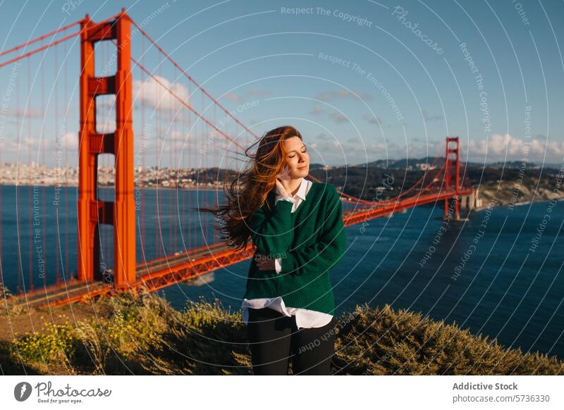 A young woman enjoys the warmth of the spring sun with the iconic Golden Gate Bridge and San Francisco skyline in the distance landmark suspension bridge sea