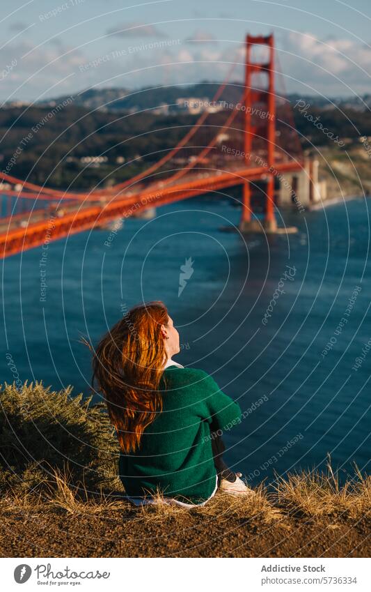 A woman sits in contemplation, gazing out at the Golden Gate Bridge and the San Francisco skyline, immersed in the beauty of spring view landmark