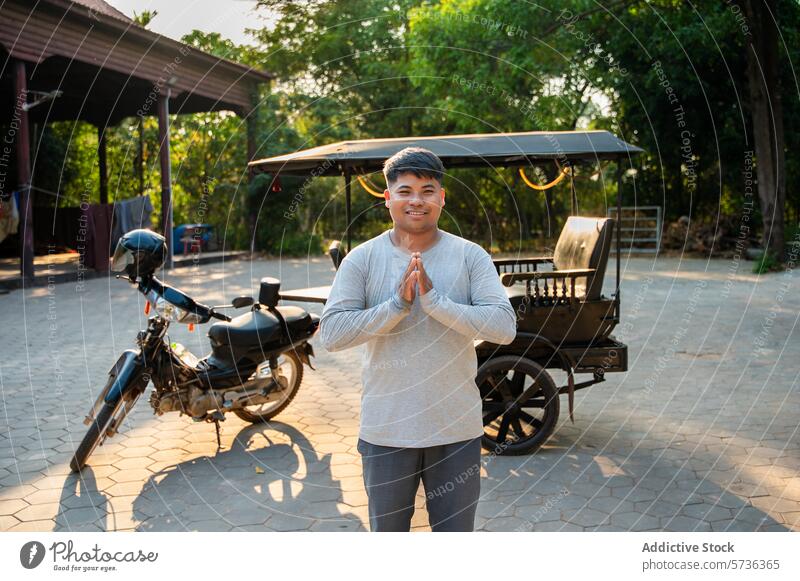 Young man with traditional greeting outdoors near a motorcycle namaste smile tuk-tuk young asian casual clothing travel culture respect polite happiness joy