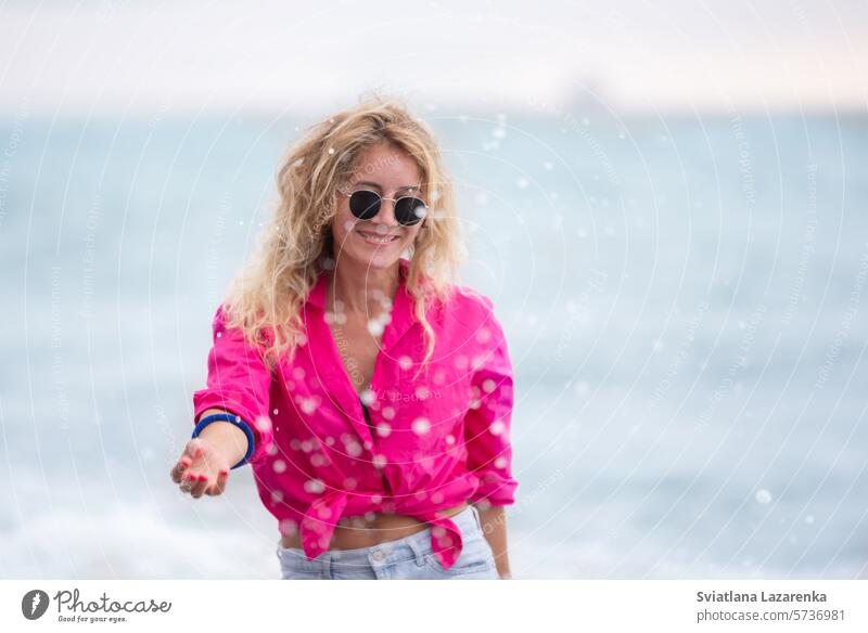 A beautiful woman in sunglasses and a pink shirt splashes sea water. outdoor summer one person caucasian fun nature smiling women cheerful lifestyle happiness