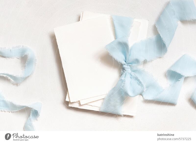 Cards tied with a light blue ribbons on white table top view, copy space, wedding stationery mockup card romantic bow silk spring mothers day pastel blank love