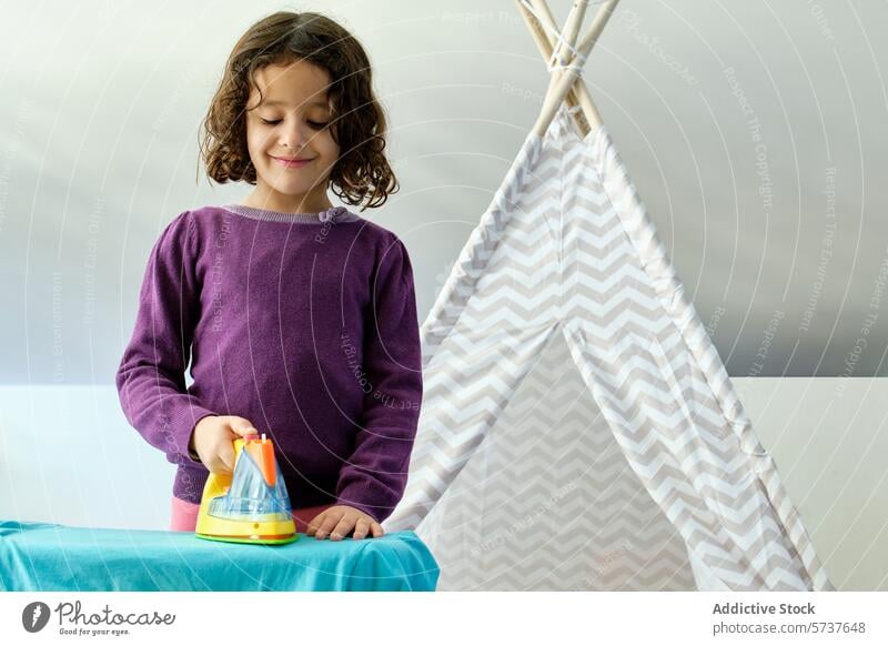 Girl creating pixel art with colorful hama beads girl child play ironing craft activity creativity focus purple sweater playful teepee tent indoor hobby