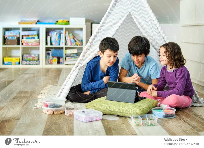 Siblings enjoying tablet time inside a play tent children siblings indoor cozy hama beads boy girl engrossed looking at screen playroom interactive technology