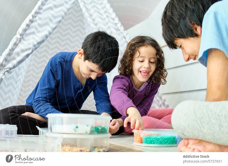 Siblings having fun with hama beads at home child play creativity siblings boy girl indoor joy concentration colorful craft room cozy looking away playtime