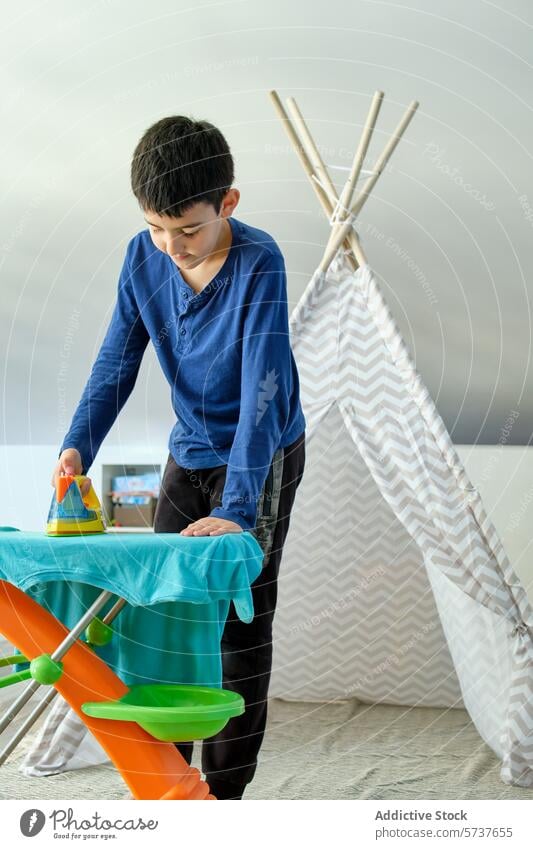 Boy playing with iron on a colorful cloth boy child ironing toy imagination childhood domestic teepee playroom activity indoor learning skill t-shirt