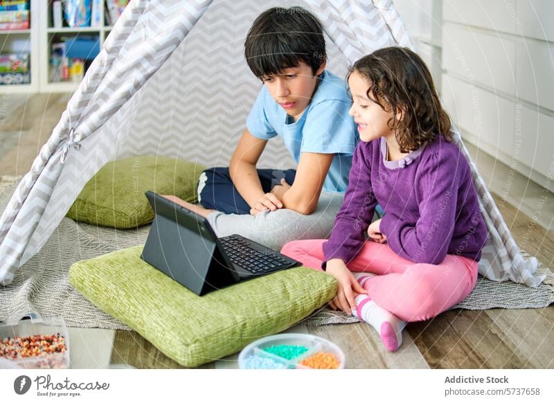 Siblings engaging in creative play with hama beads and tablet children boy girl siblings cozy tent imagination digital literacy playtime indoors leisure floor