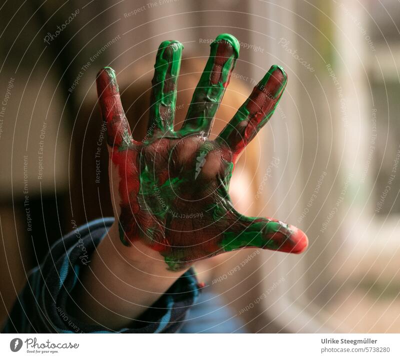 A child holds his painted hand up to the camera Creative with children Life with children Joy fun Green variegated Red Finger paint Study children's art Art
