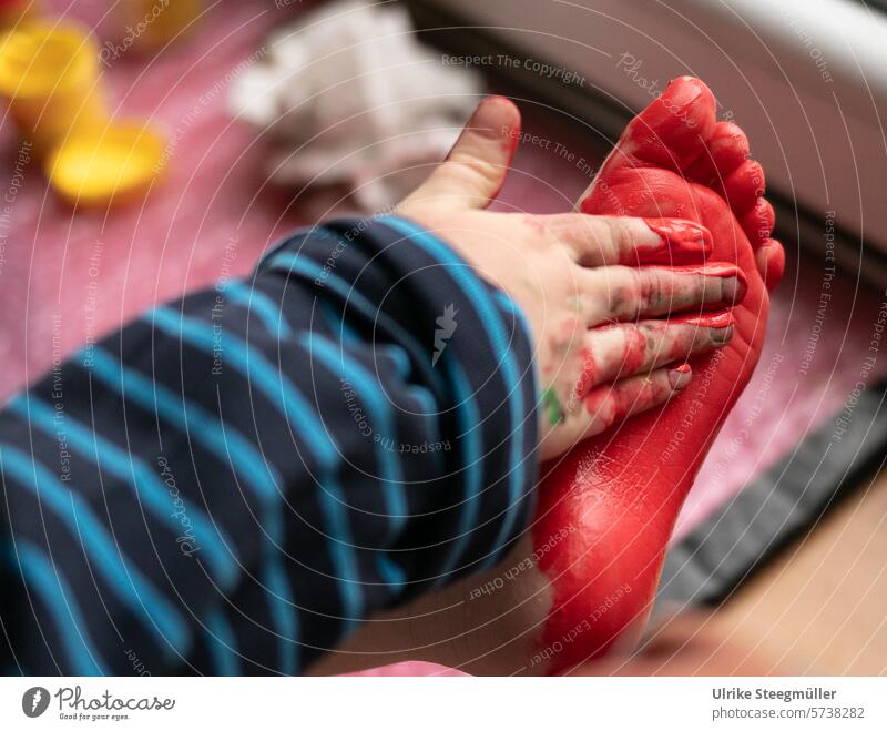 A child paints his foot with his hand and red finger paint Feet Hand Painting (action, artwork) Red Art children's art Life with children Colour photo