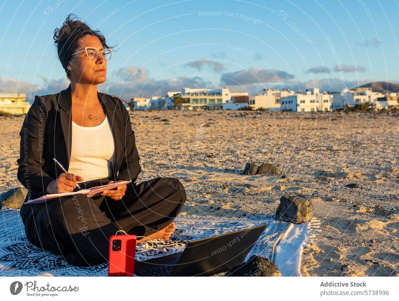 Digital nomad working on beach at sunset woman digital nomad laptop smartphone taking notes remote work freelance travel thoughtful lifestyle sandy evening