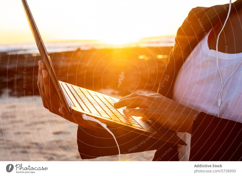 Anonymous digital Nomad Working on Laptop at Sunset Beach digital nomad sunset beach laptop work remote headphones silhouette glow ocean technology mobile