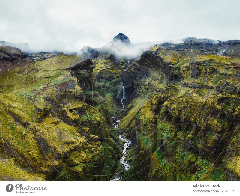 Misty Mountains and Waterfall in Iceland's Rugged Landscape iceland mountain mist waterfall landscape green rugged terrain scenic view outdoor nature travel
