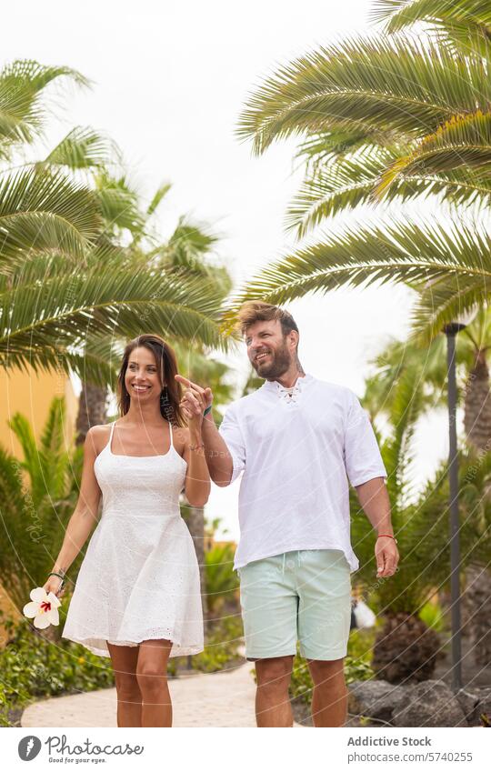 Couple walking together in a tropical setting couple vacation palm path relax happy hand-in-hand stroll man woman summer leisure travel love romance holiday