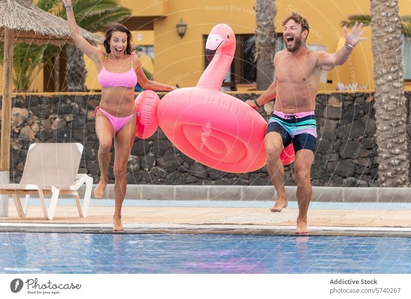 Joyful couple playing with inflatable flamingo by the pool playful joy swimwear vacation leisure fun summer holiday excitement happiness outdoor water poolside