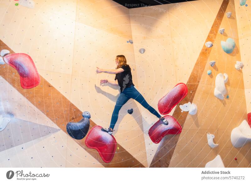 Indoor rock climbing - an active woman reaching out indoor sport fitness activity climbing wall dynamic motion hold grip hobby challenge determination strength