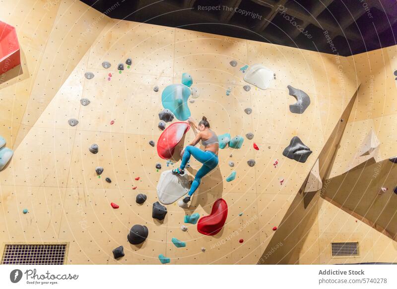 Active woman conquering an indoor bouldering wall climbing athlete fitness sport challenge holds active workout health strength exercise hobby leisure