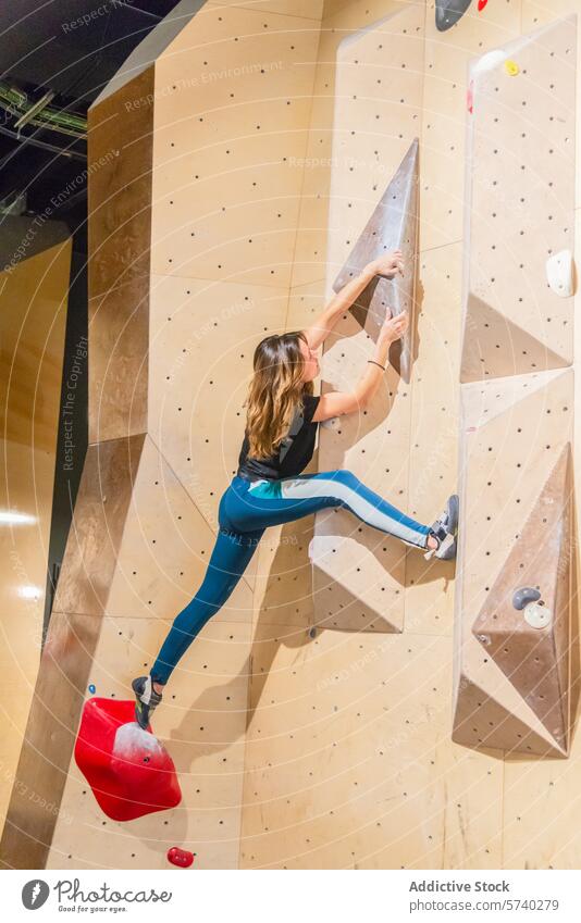 Woman Scaling an Indoor Climbing Wall with Determination woman indoor climbing wall agility strength reach challenging hold masterful scale exercise fitness