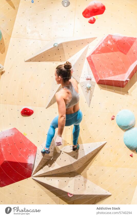 Female athlete climbing an indoor bouldering wall climber female strength agility gym ascent focus colorful sports recreation fitness exercise training active