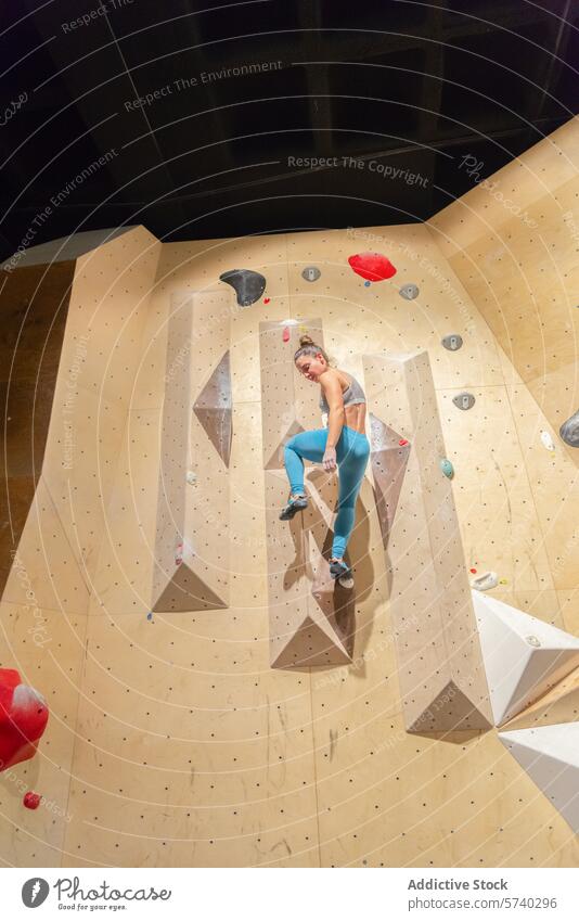 Athletic woman climbing an indoor rock wall athletic sport fitness challenge holds climber activity healthy lifestyle exercise strength training bouldering grip