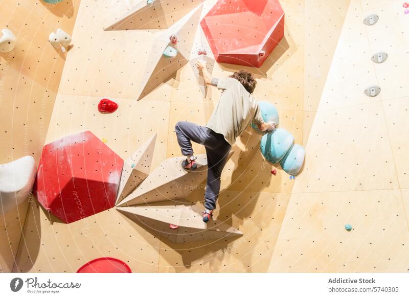 Young climber practicing on an indoor bouldering wall colorful challenging route practice climbing sport reach balance athletic gym fitness strength workout