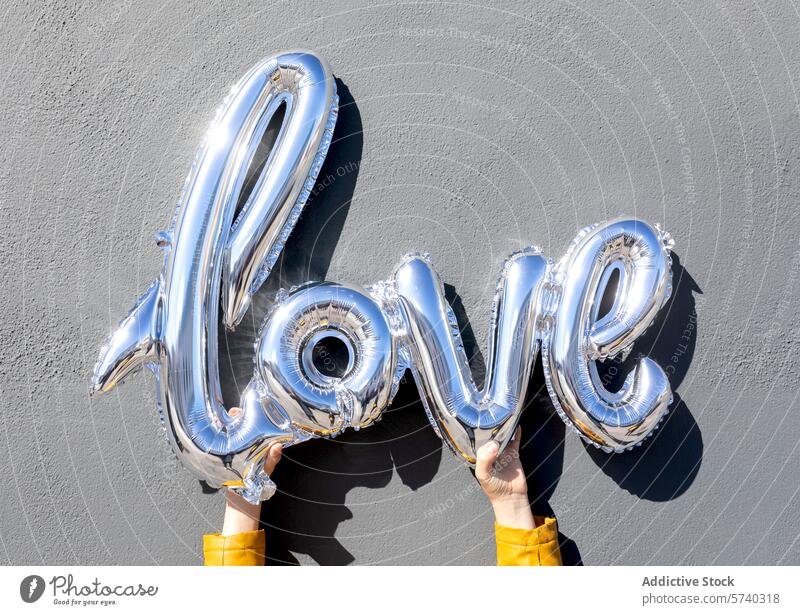 Holding silver balloon letters spelling love hand hold word gray background celebration decoration valentine romance shiny metallic helium inflate anniversary