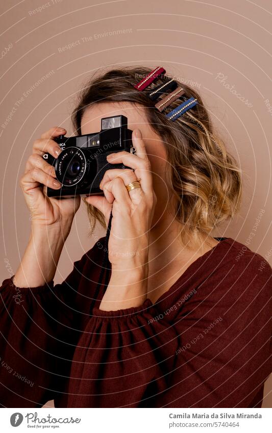 Young woman looking through a vintage camera. Photo in studio with isolated background. adult beautiful beauty blonde caucasian concept creativity expression