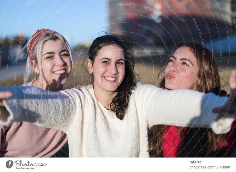 Joyful friends posing with arms out in sunlight. friendship joy women smiling outdoors playful sunny happy casual youth together fun bonding relaxed cheerful