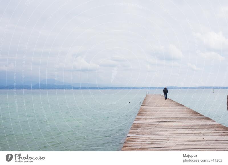 Unrecognizable man standing on pier over Garda lake horizon perspective tranquility port scape idyllic discovery seascape vacations silence awe backgrounds