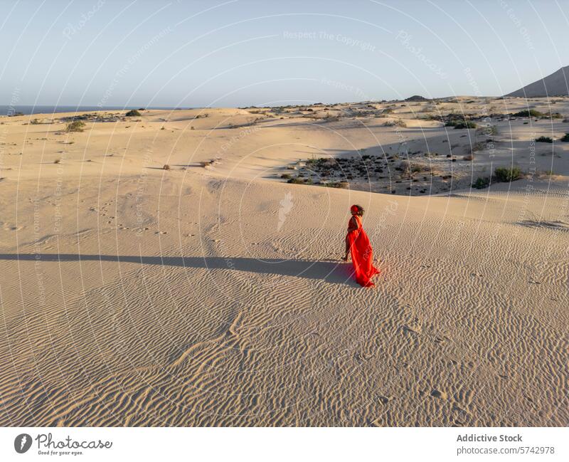 Elegant woman in red dress strolls through desert dunes sand wander elegant contrast serene landscape flowing vast away gaze peaceful tranquil outdoors nature