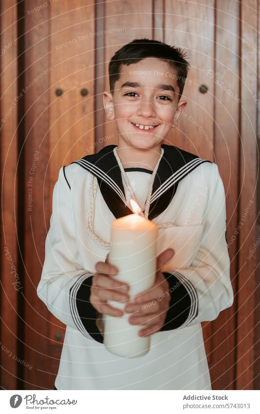 A young boy in his First Communion attire holds a lit candle, symbolizing the light of faith, with a warm smile smiling portrait communion celebration happy