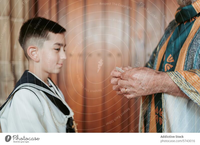 A young boy in First Communion attire looks on as anonymous priest prepares to give the blessing, a moment of faith and tradition child ceremony anticipation