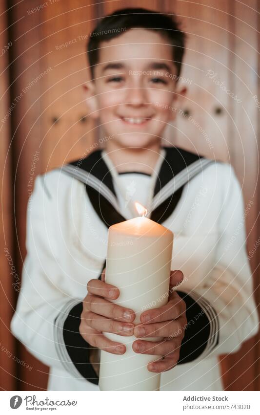 A content young boy in First Communion dress holds a candle, its flame symbolizing the light of Christ, with a gentle focus smile celebration religious happy