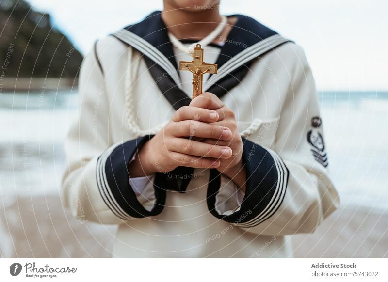 Focused image of anonymous child's hands reverently holding a golden crucifix during a First Communion ceremony by the sea close-up reverence religious symbol