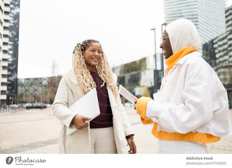 Smiling Women Conversing Outdoors in Urban Setting woman female conversation smiling city street urban outdoors friendly camaraderie friendship meeting casual